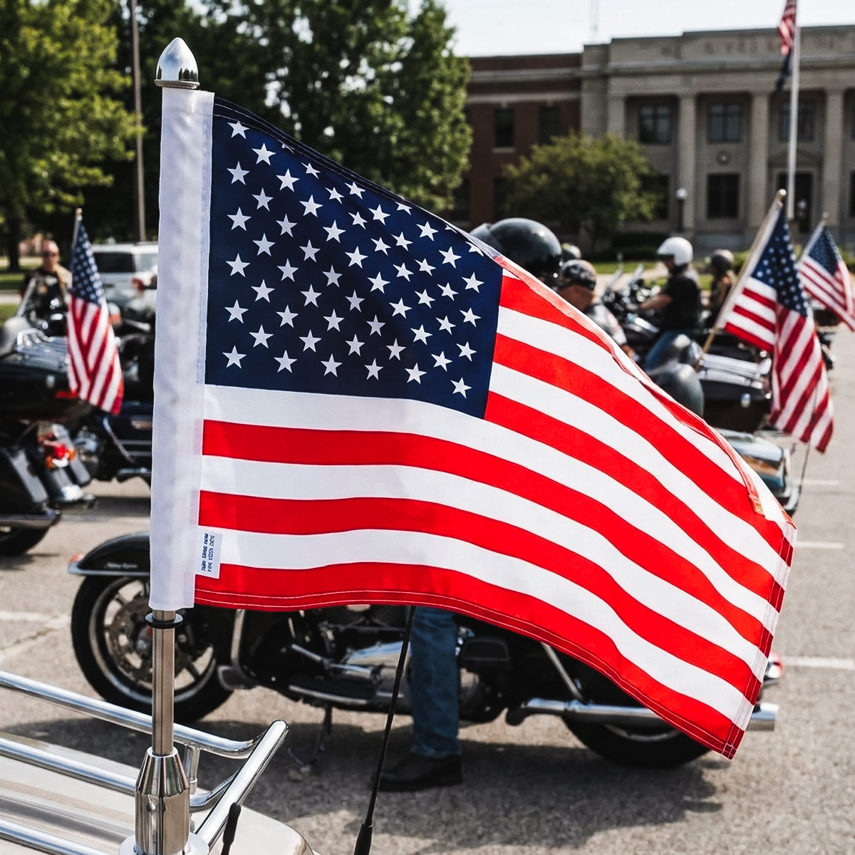 American flag held by a person with motorcycles and other people in the background