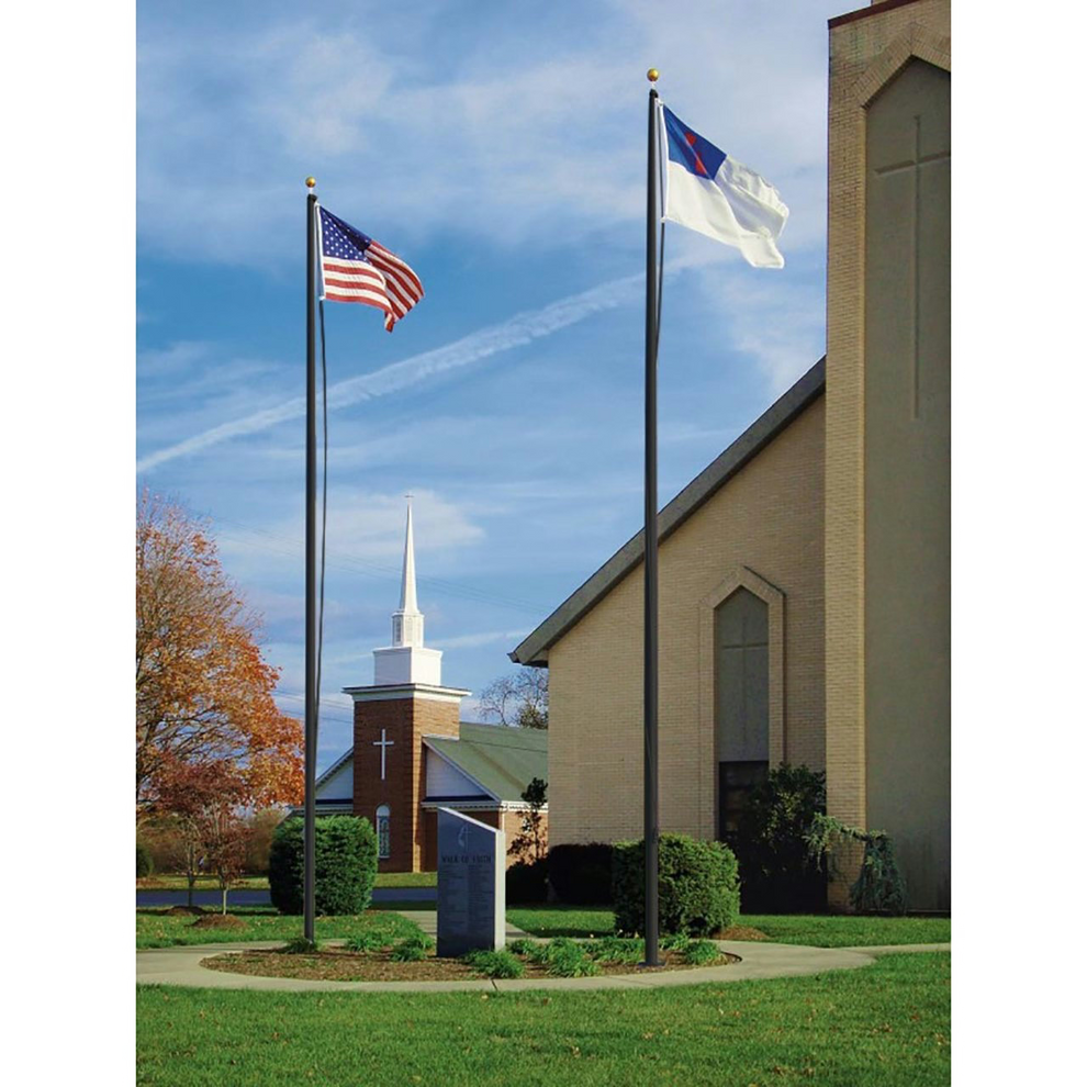 A tall aluminum flagpole with a gold anodized ball on top, displaying two flags, installed outside near a church.