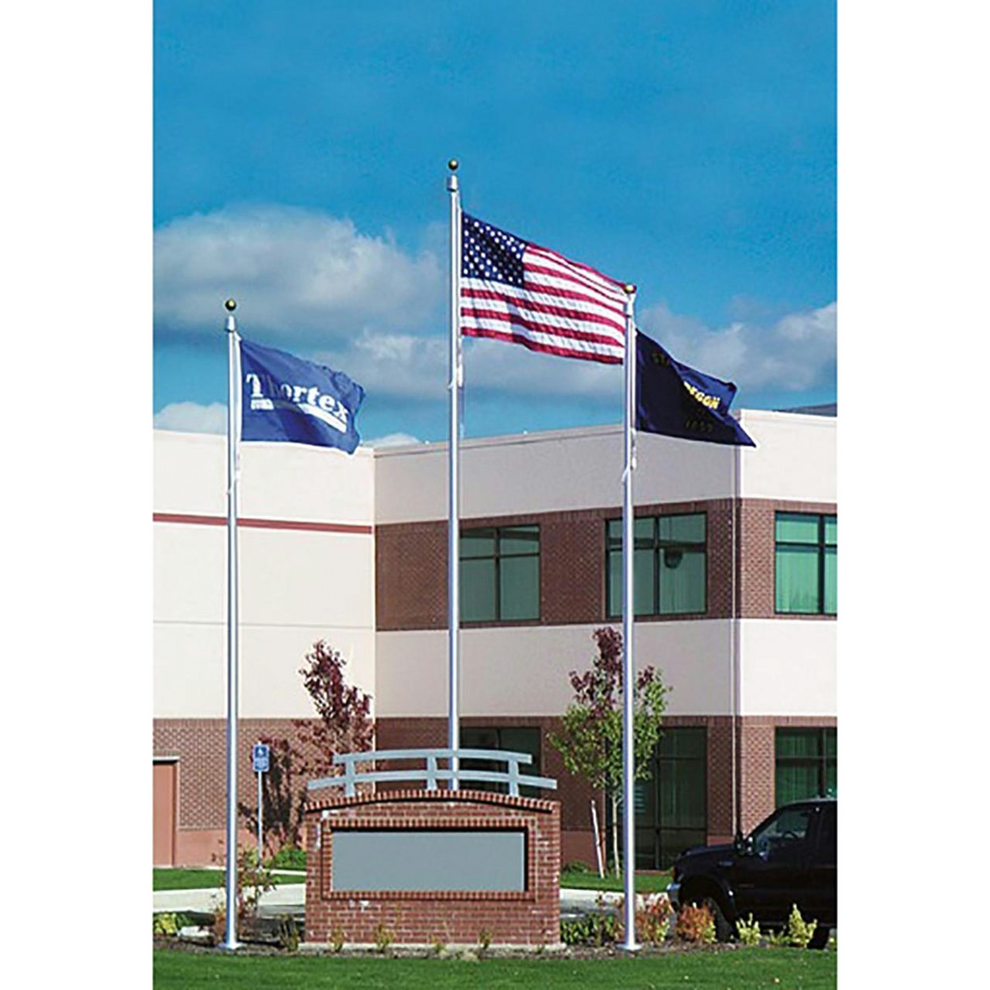 American flag on a flagpole with two other flags on flagpoles in front of a building