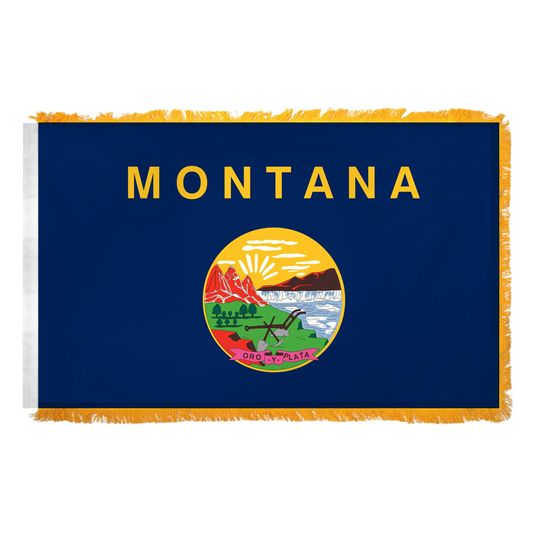 State of Montana flag with 'MONTANA' printed in large, gold all-caps letters across the top. Centered below the text is the full-color state seal, depicting a landscape with the Rocky Mountains, the Great Falls of the Missouri River, a plow, a shovel, and a pick. A ribbon at the bottom of the seal reads the Spanish motto 'ORO Y PLATA'. Flag features yellow fringe.