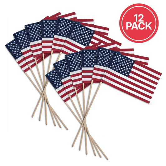 Twelve small American flags on wooden sticks, arranged in two overlapping groups on a white background, with a red circular badge in the top right that reads '12 PACK'.