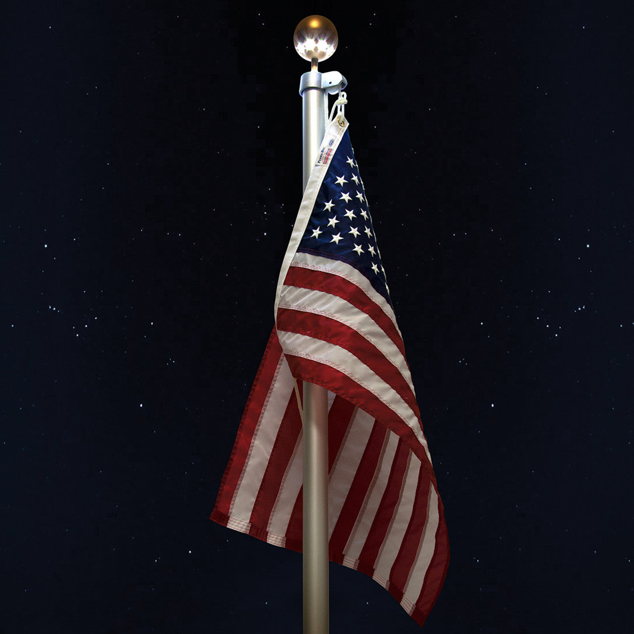 American flag hanging on a flagpole with a globe light against a starry night sky.