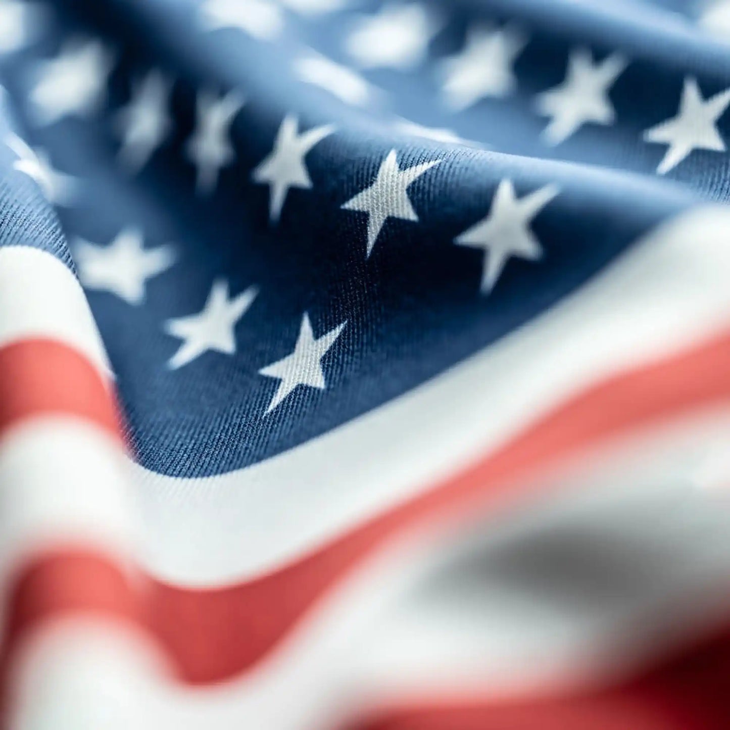 Close-up of American flag fabric showing detailed texture, vibrant red and white stripes, and crisp white stars.