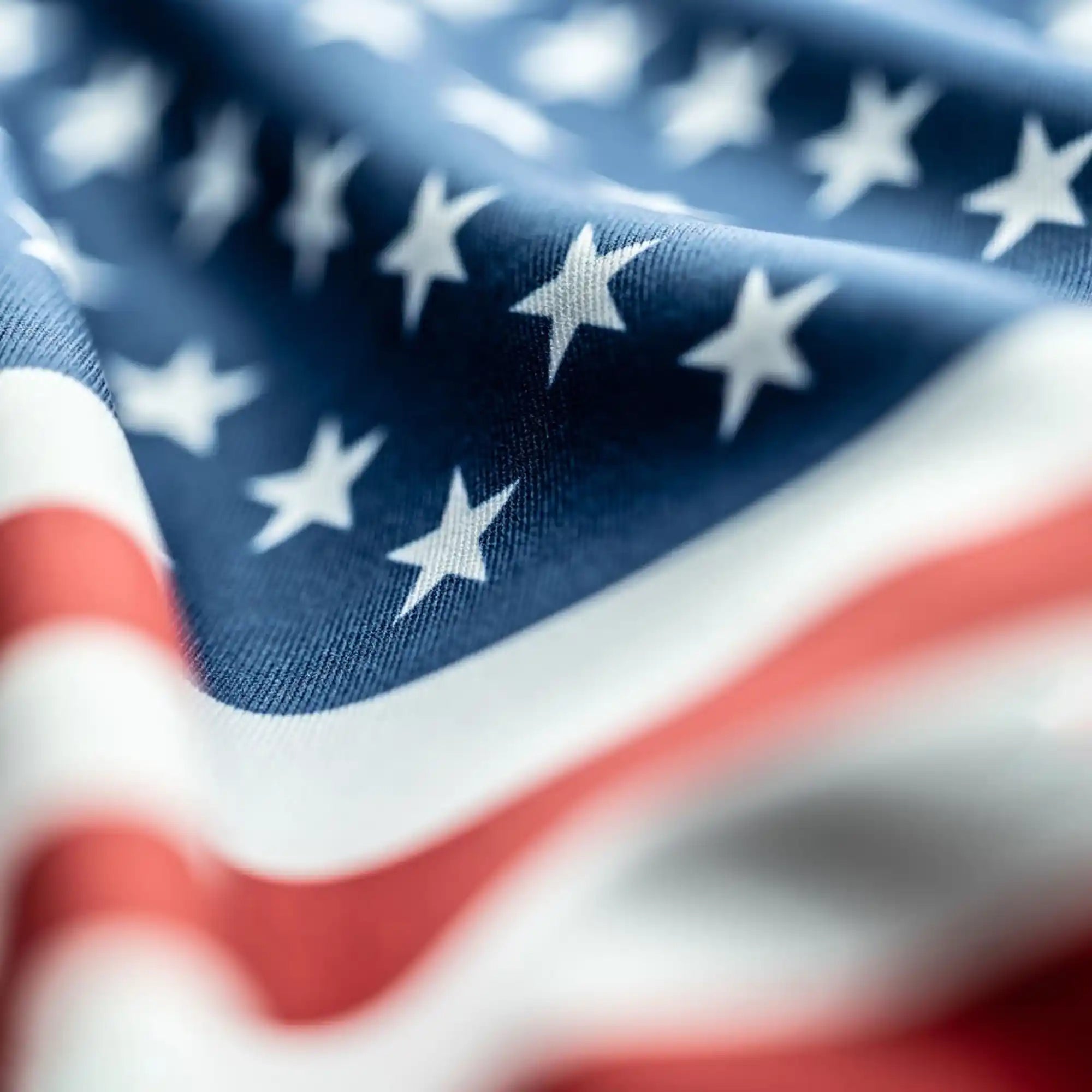 Close-up of American flag fabric showing detailed texture, vibrant red and white stripes, and crisp white stars.