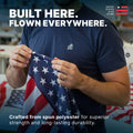 A craftsman inspecting an American flag made of spun polyester, emphasizing superior strength and long-lasting durability.