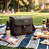 Picnic setup with a cooler bag, food items, and drinks on a blanket in a park.