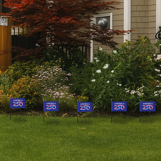 Set of five blue America 250 stick flags with white text on a grassy lawn.