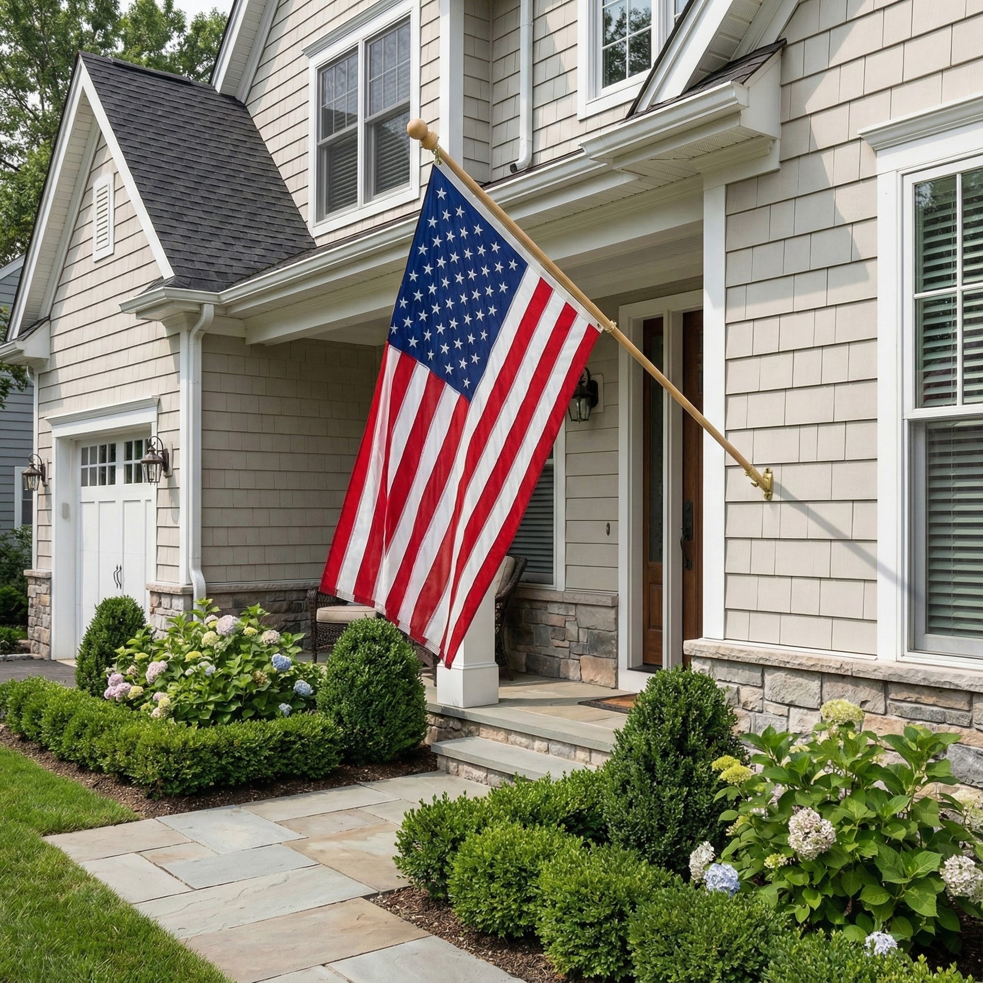 American flag waving in front of a house with a well-maintained garden.