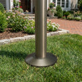 Metal flagpole with base on grass in a garden setting