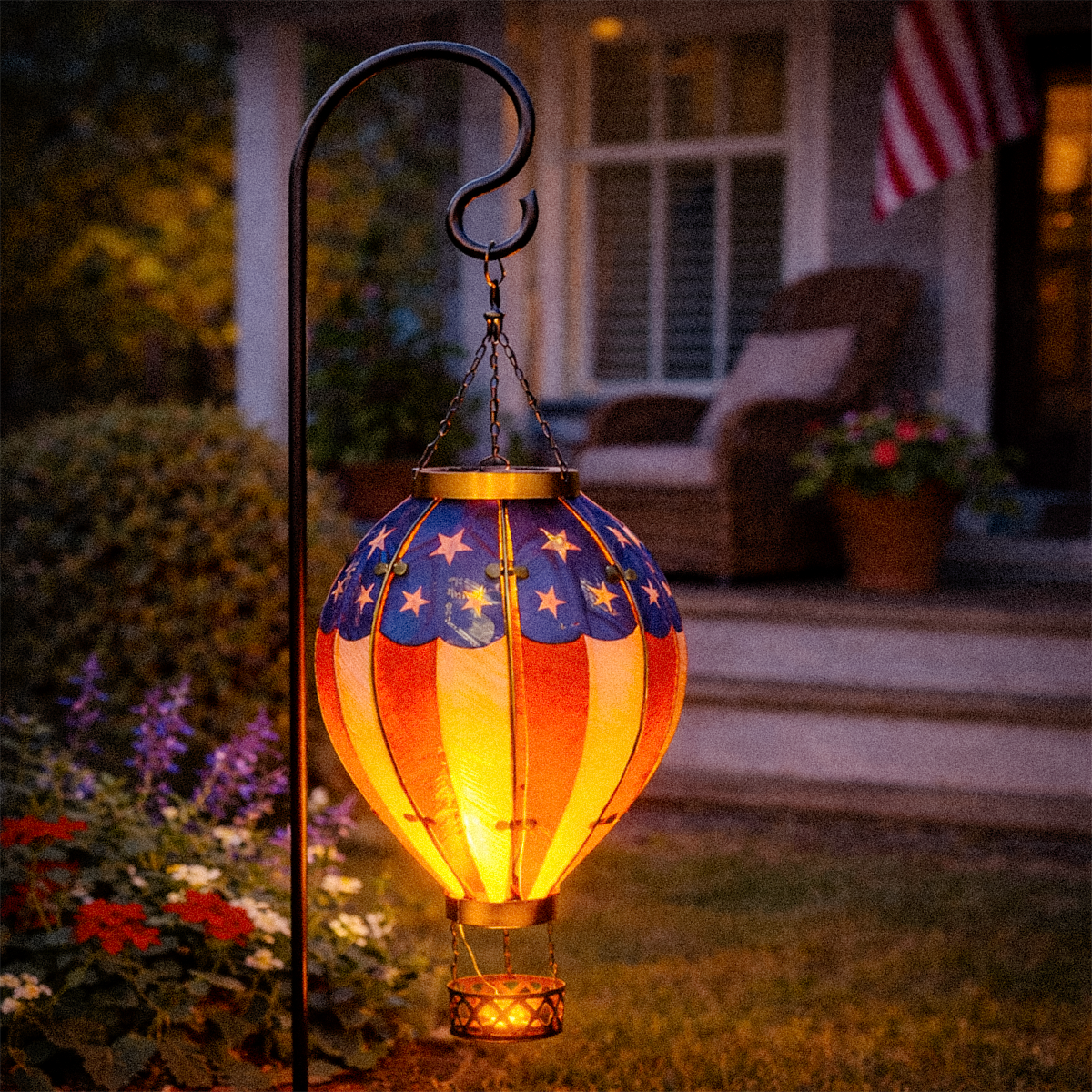 Decorative outdoor lantern with American flag design on a garden stand.