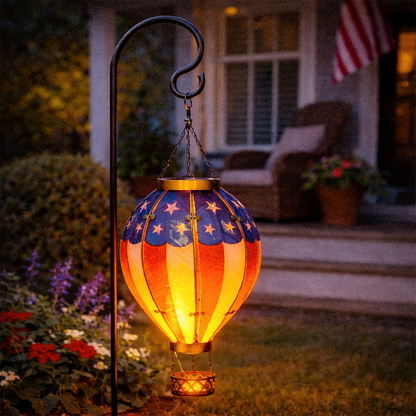 Decorative outdoor lantern with American flag design on a garden stand.