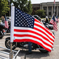 American flag held by a person with motorcycles and other people in the background