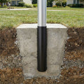 Metal pole with black base embedded in concrete in a grassy area