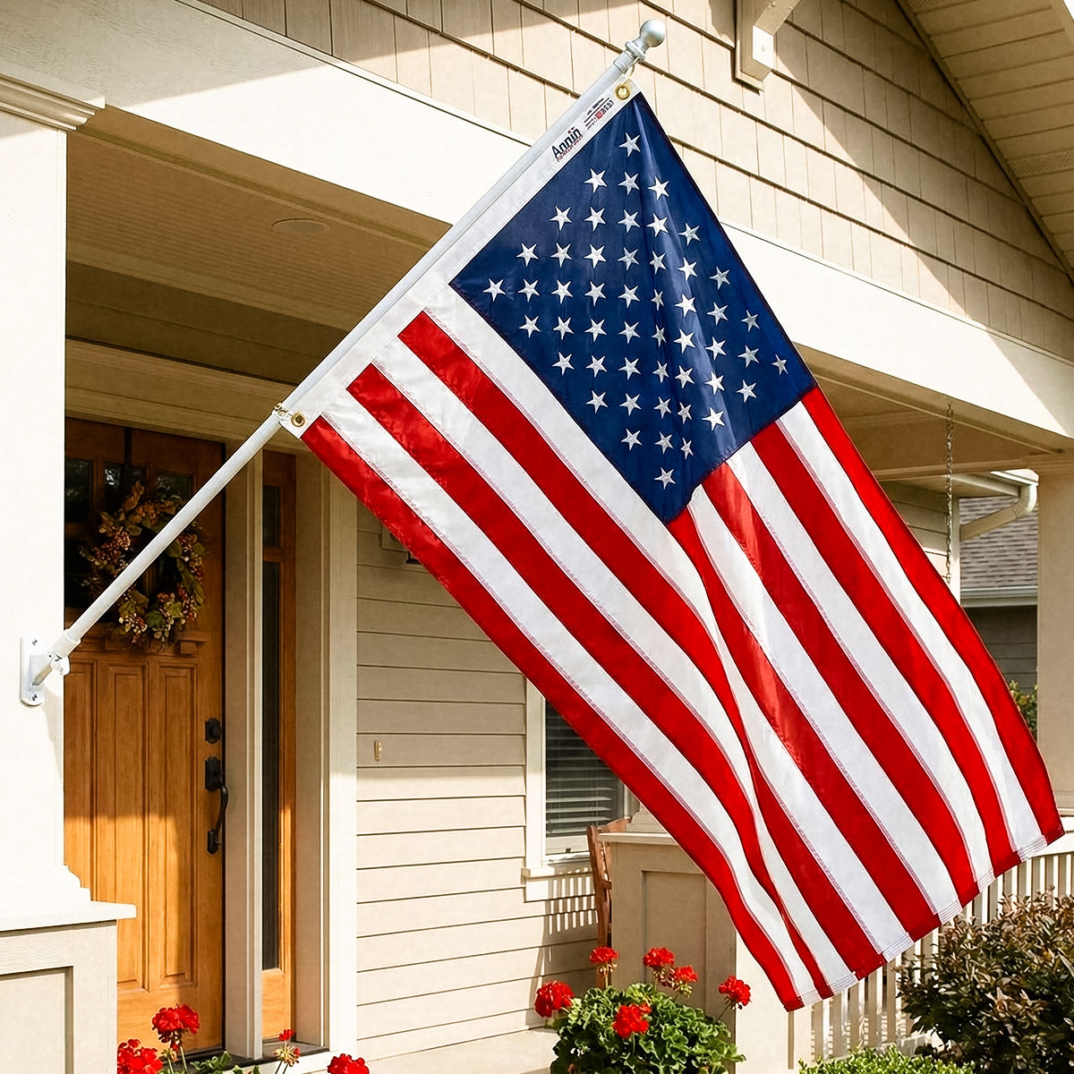 American flag waving outside a house with a wooden door and flowers.