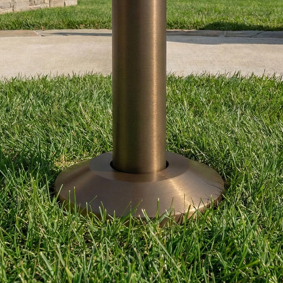 Bronze-colored metal post base on grass