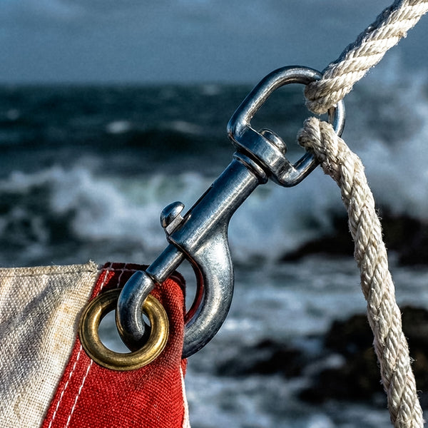 Close-up of a metal hook with a rope against a blurred ocean background