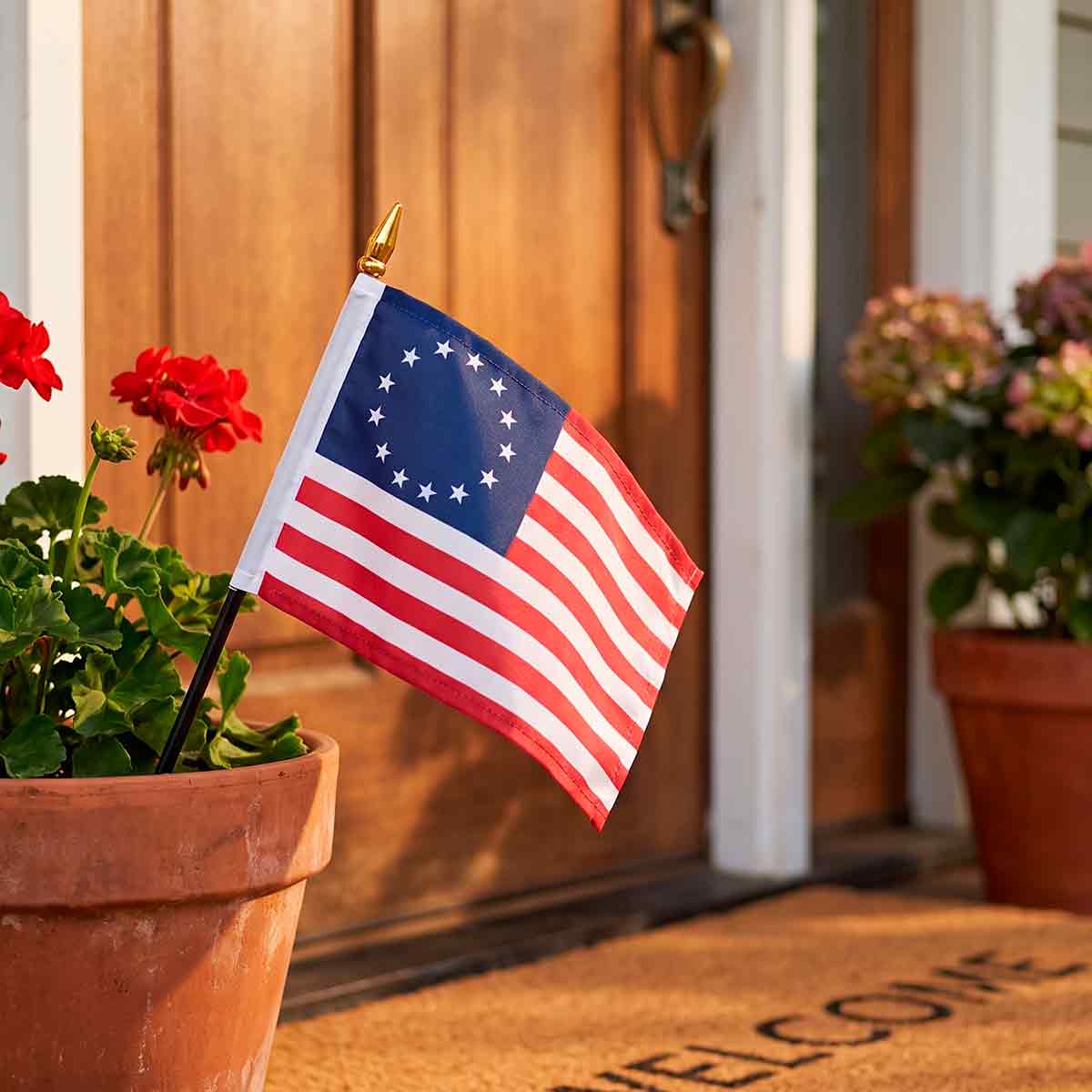 Betsy Ross flag on a stick in a flower pot by a front door