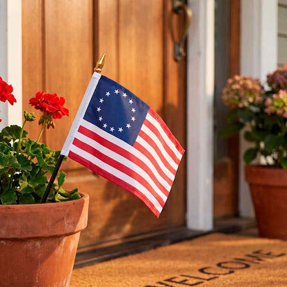 Betsy Ross flag on a stick in a flower pot by a front door