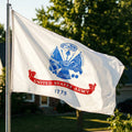 United States Army flag waving in the wind with trees in the background