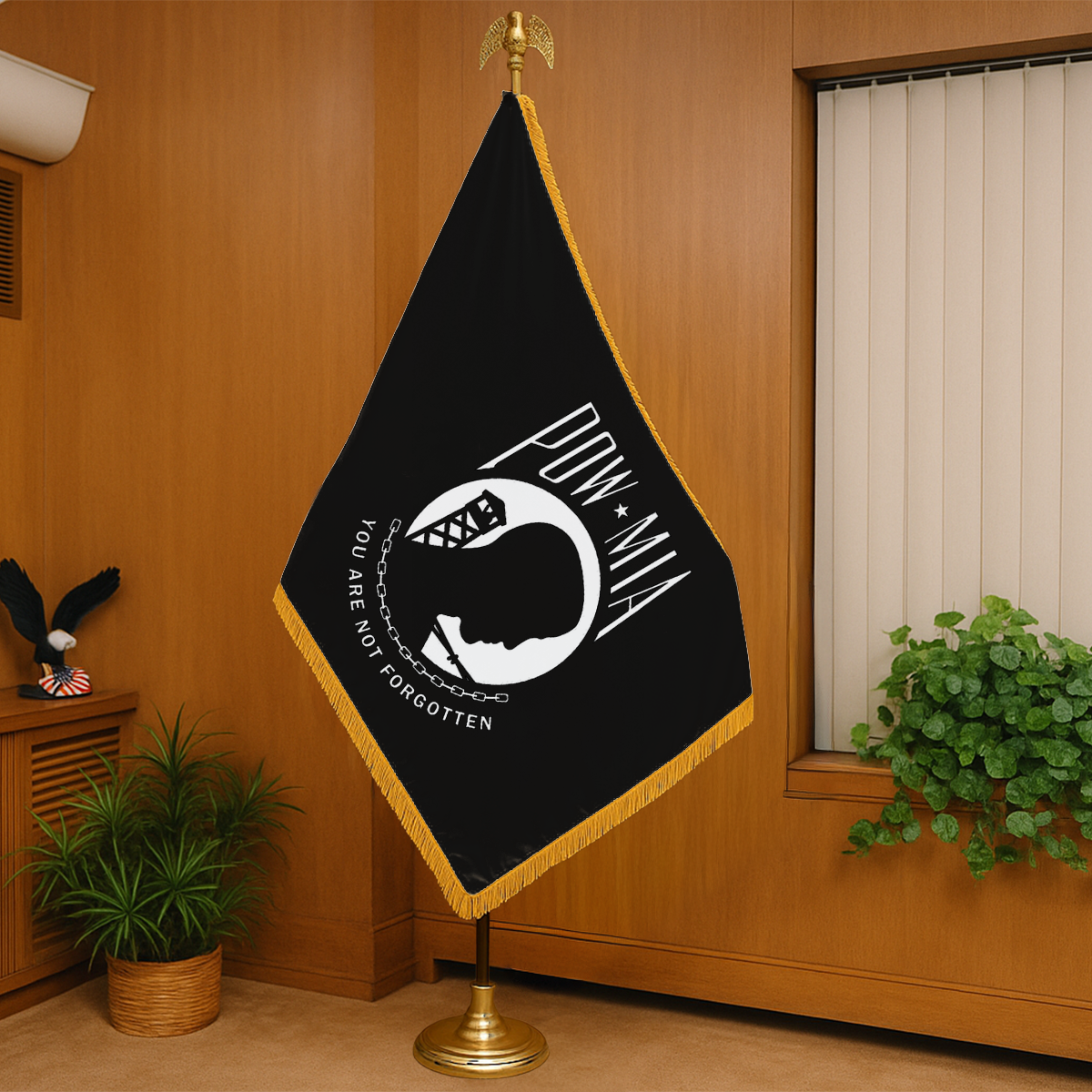 Black POW MIA flag with white design and text on a stand in a room with wooden walls and plants.