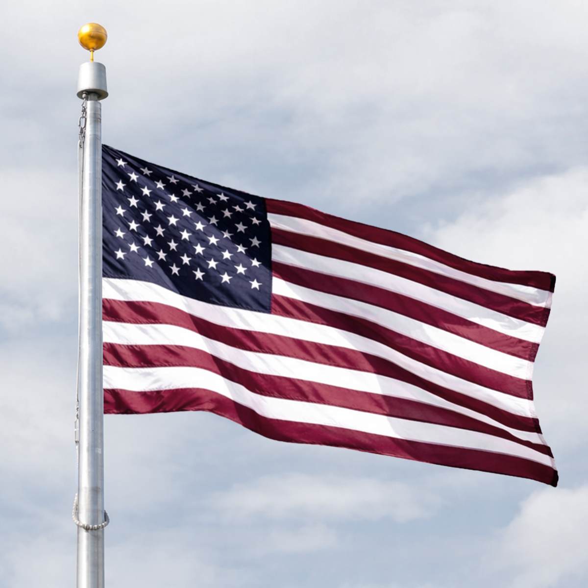 American flag waving on a flagpole against a cloudy sky
