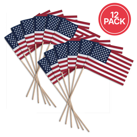 Twelve small American flags on wooden sticks, arranged in two overlapping groups on a white background, with a red circular badge in the top right that reads '12 PACK'.