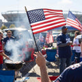 Small American stick flag held at a tailgate party outside a stadium, patriotic hand flag for sports events and outdoor celebrations