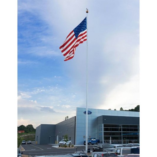 Car dealership with an American flag waving in front against a blue sky.