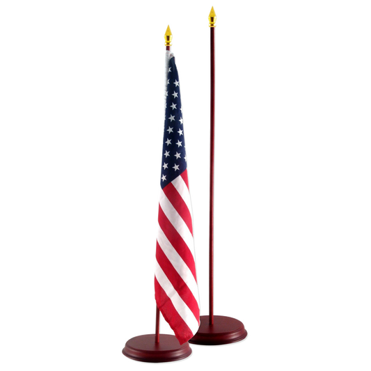 American flag on a small desk flagpole with gold spear finial and round base, beside an empty matching pole.
