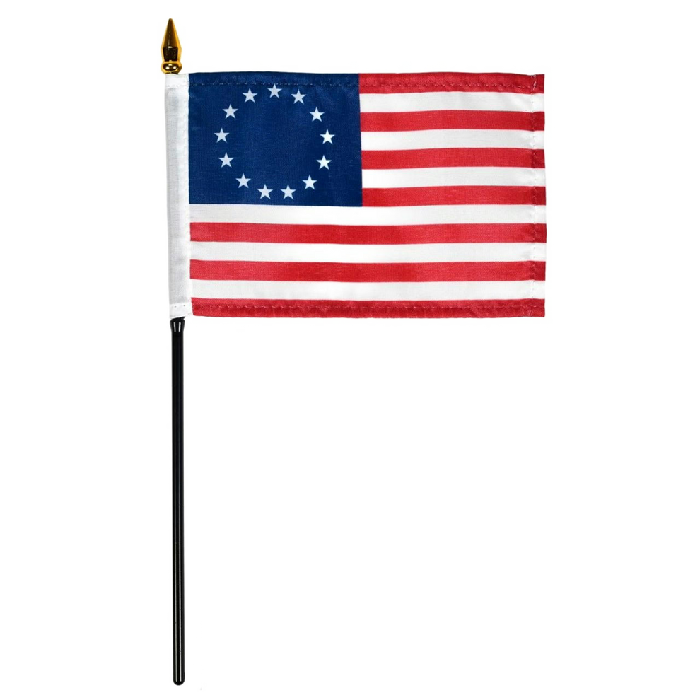 Betsy Ross style American flag with 13 stars in a circle on a blue canton and red and white stripes, mounted on a black stick with a gold spear finial, isolated on a white background.
