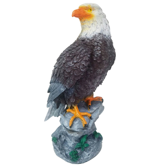 Statue of a bald eagle perched on a rock with a white background