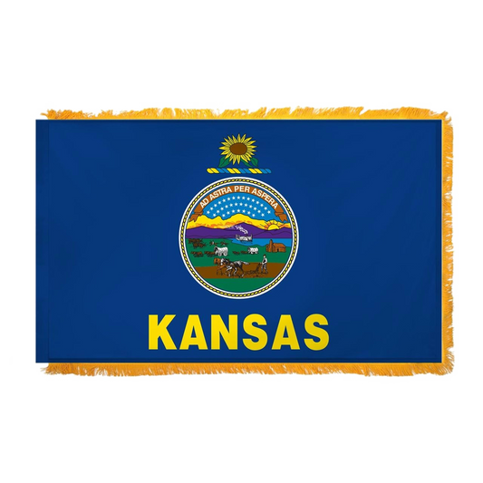State of Kansas blue flag with Kansas state seal in the center, depicting a landscape with a rising sun, a steamship, a settler plowing a field, a covered wagon train, and Native Americans hunting buffalo. Above the scenery is the Latin motto 'AD ASTRA PER ASPERA'. Above the seal sits a gold and blue sunflower twist, and the word 'KANSAS' is printed in large, gold all-caps letters directly below the seal.  Flag features yellow fringe.