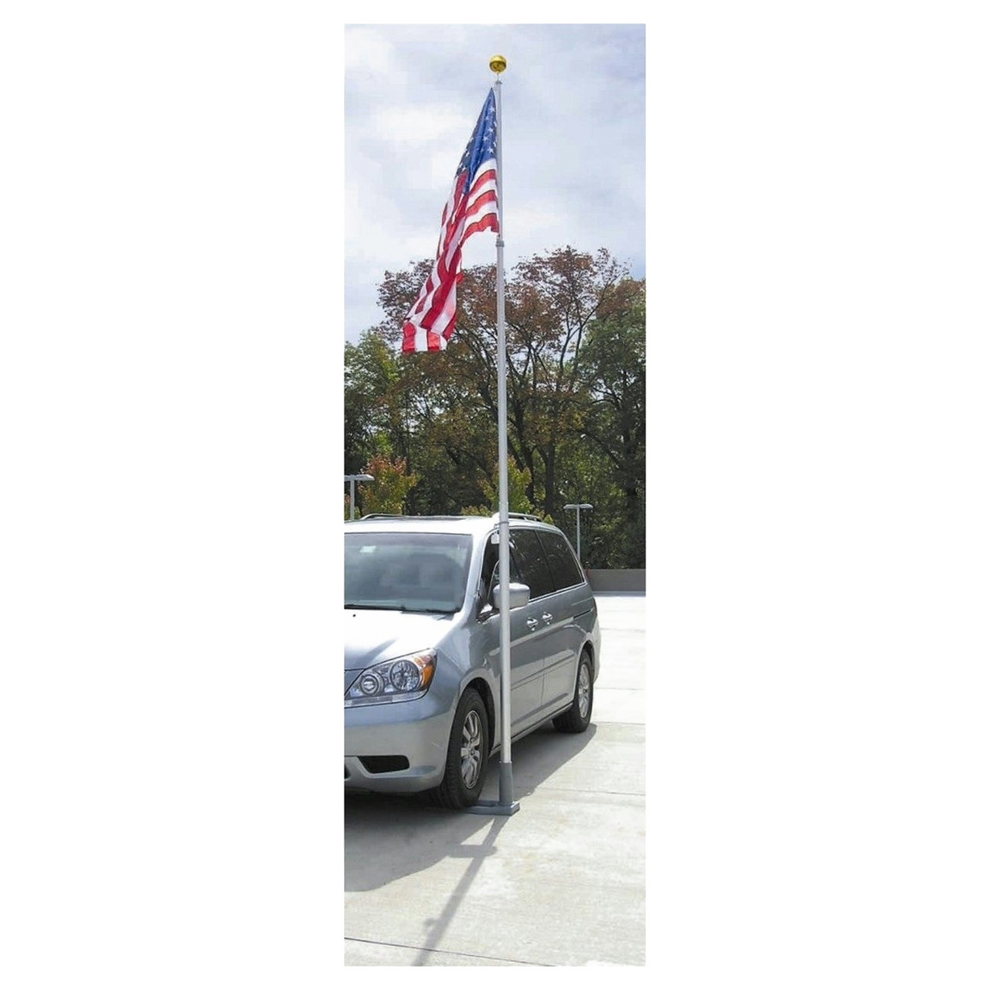 Silver minivan parked on a driveway with an American flag on a pole.