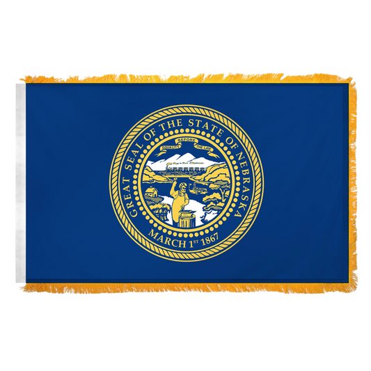 State of Nebraska state flag featuring the gold and silver state seal with the motto 'Equality Before the Law' on a solid dark blue field.  Seal includes a steamboat on a river, a train moving across mountains, a blacksmith at work, and a settler's cabin.  This flag features yellow fringe.