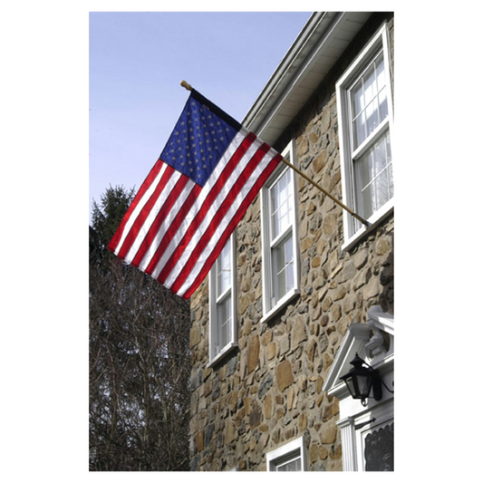 American flag waving in front of a stone building with windows.