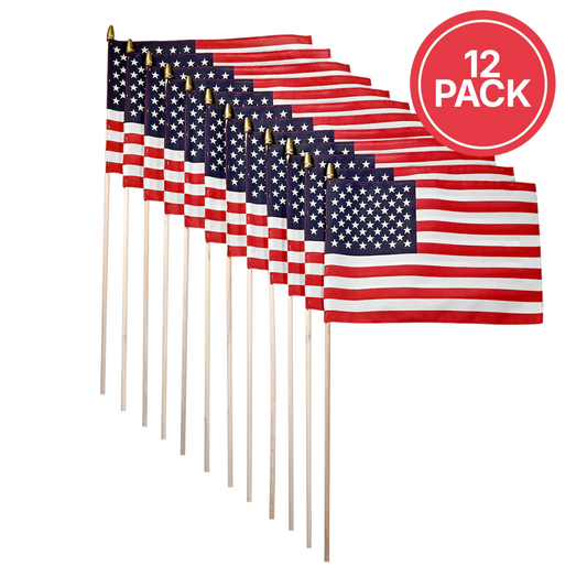 Twelve small American flags on wooden sticks arranged in a fan shape, with a red circular badge in the top right that reads '12 PACK' on a white background.