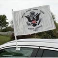 United States Coast Guard flag on a car roof with a garden and trees in the background.