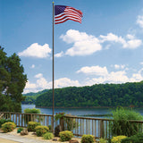 An American flag on a flagpole.  Backdrop is a body of water, either a lake or river, with trees.