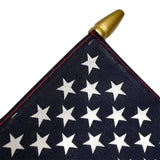 Close-up of an American flag with white stars on a blue background, featuring a gold spearhead.