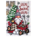 Decorative flag with Christmas gnome in a red wagon with a small house and tree, text 'Gnome Sweet Gnome' on a snowy background.