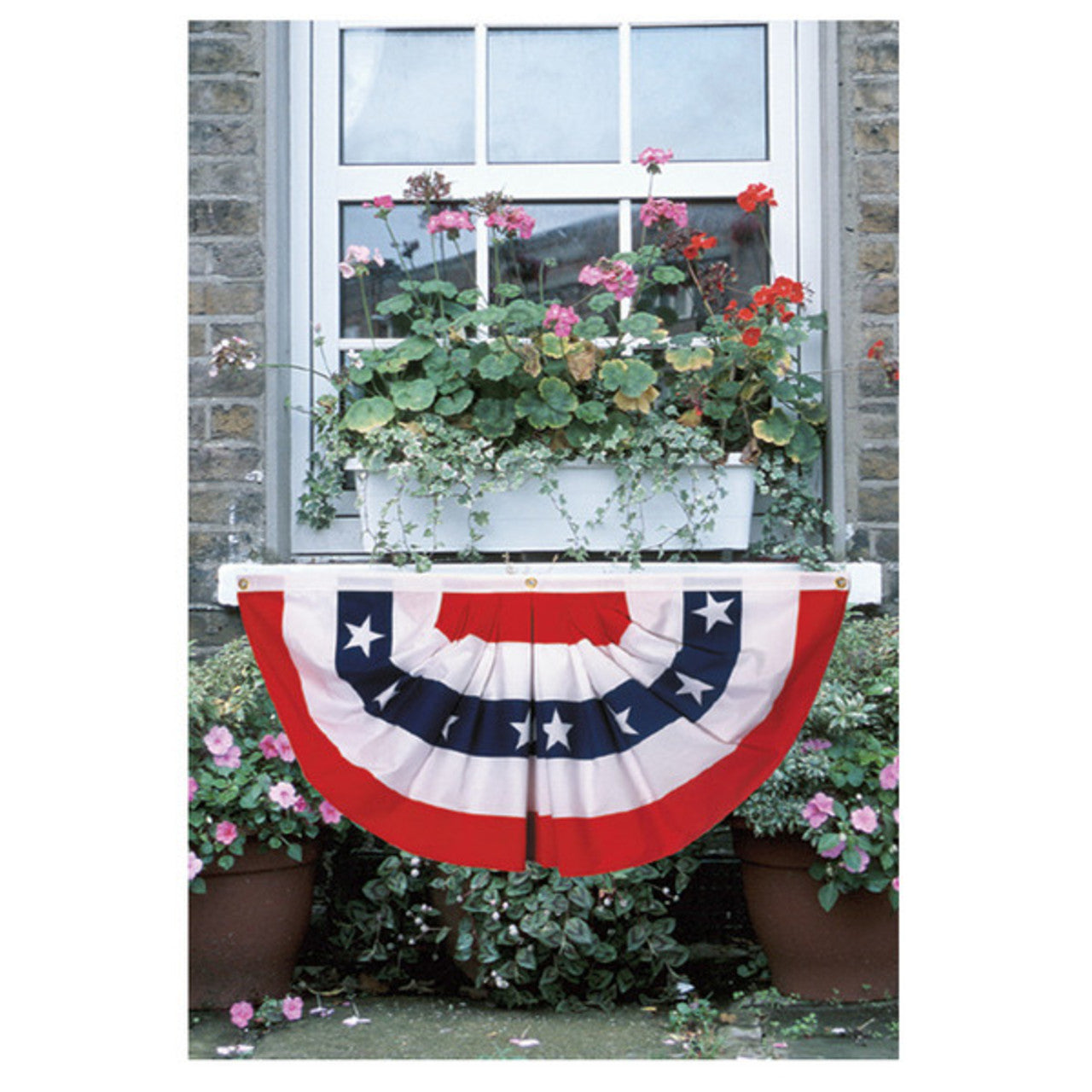 American flag bunting hanging in front of a window with flower boxes.