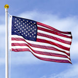 American flag waving against a blue sky with some clouds