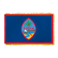 Flag of Guam with a blue background, red border, and colorful emblem featuring a palm tree, beach, and sailboat.