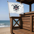 US Coast Guard flag on a wooden structure by the beach.