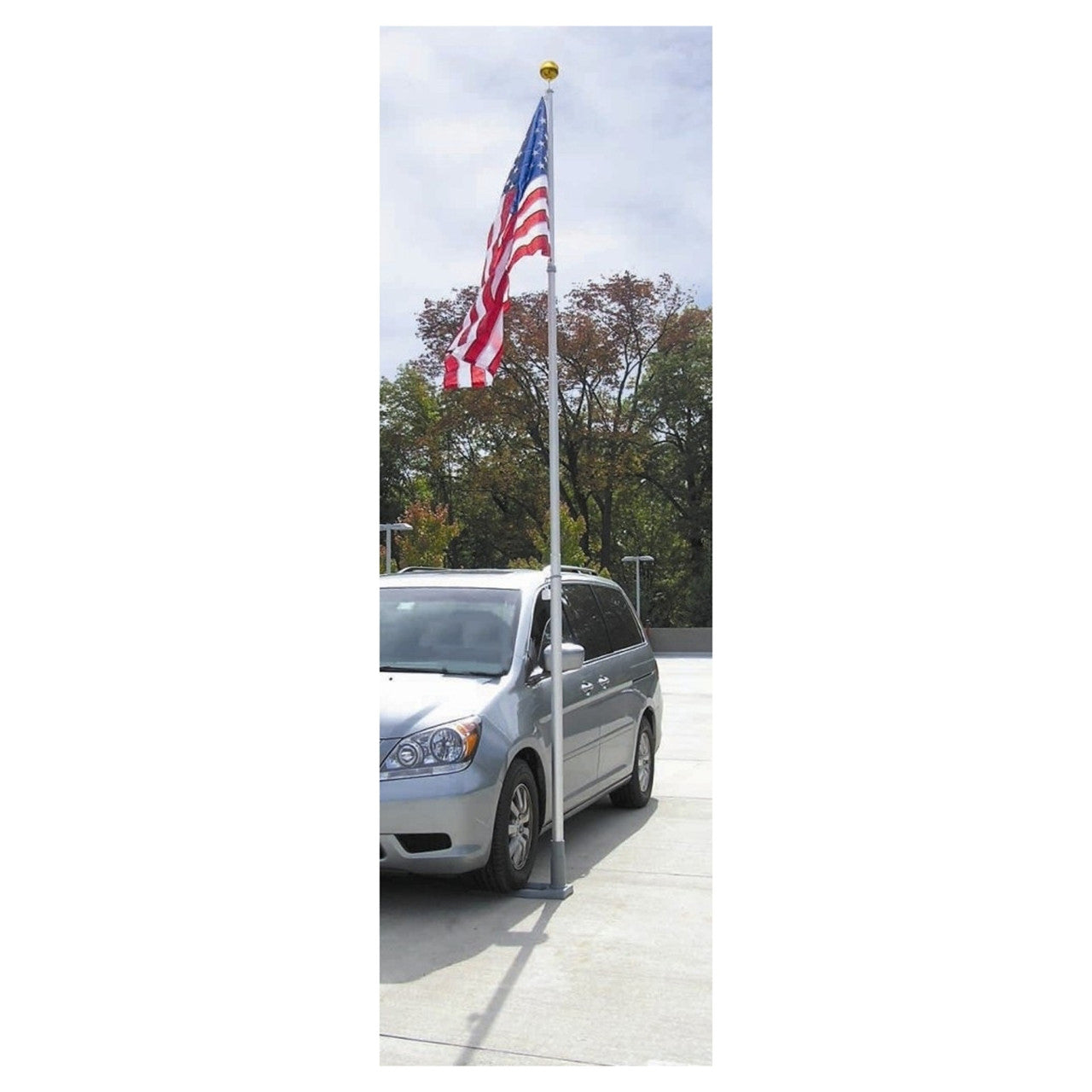 Silver minivan parked on a driveway with an American flag on a pole.