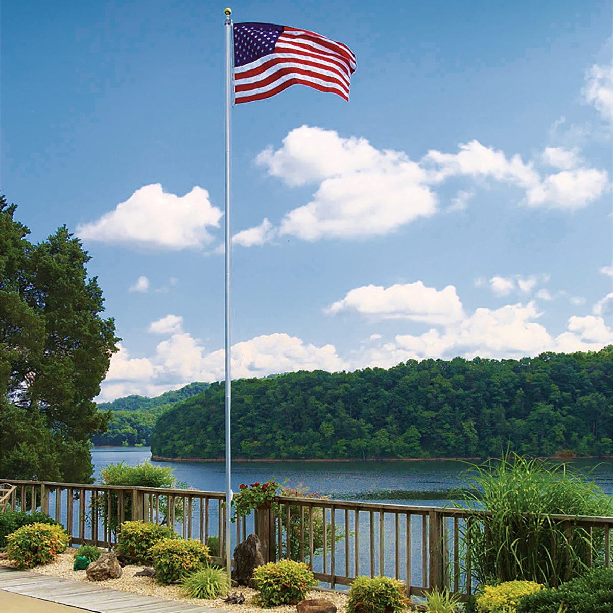 An American flag on a flagpole.  Backdrop is a body of water, either a lake or river, with trees.