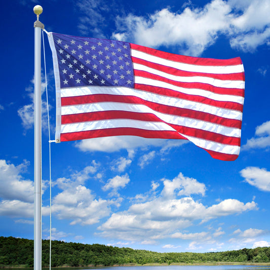 American flag waving against a blue sky with white clouds