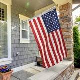 An American flag mounted on a pole, displayed in front of a house entrance.