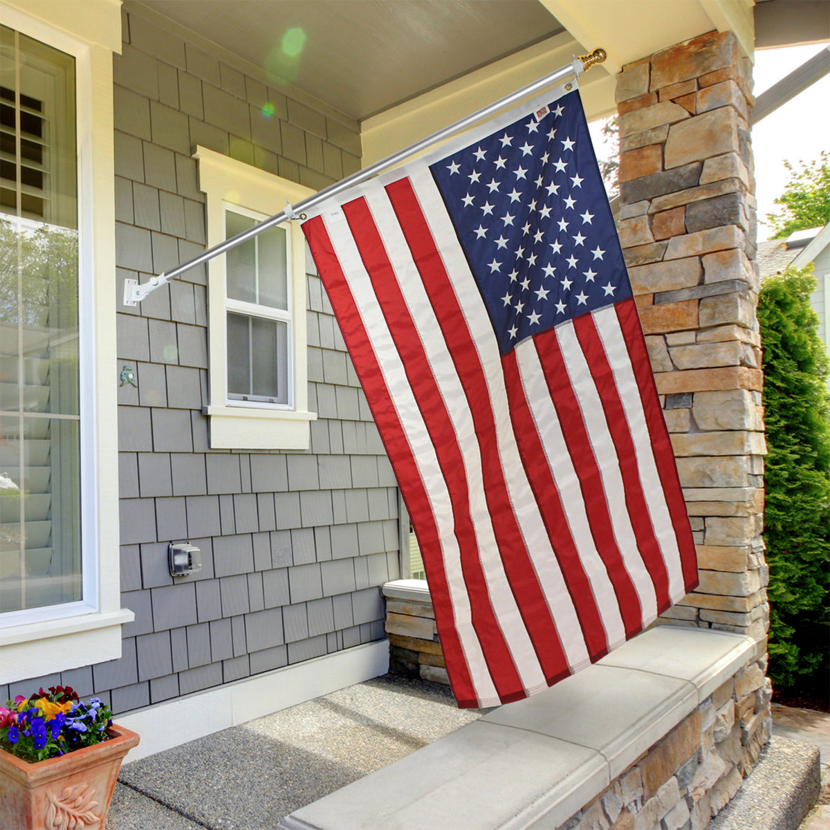 An American flag mounted on a pole, displayed in front of a house entrance.