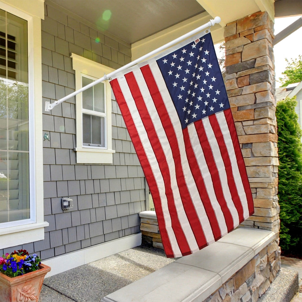 American flag hanging outside a house with stone wall and window.